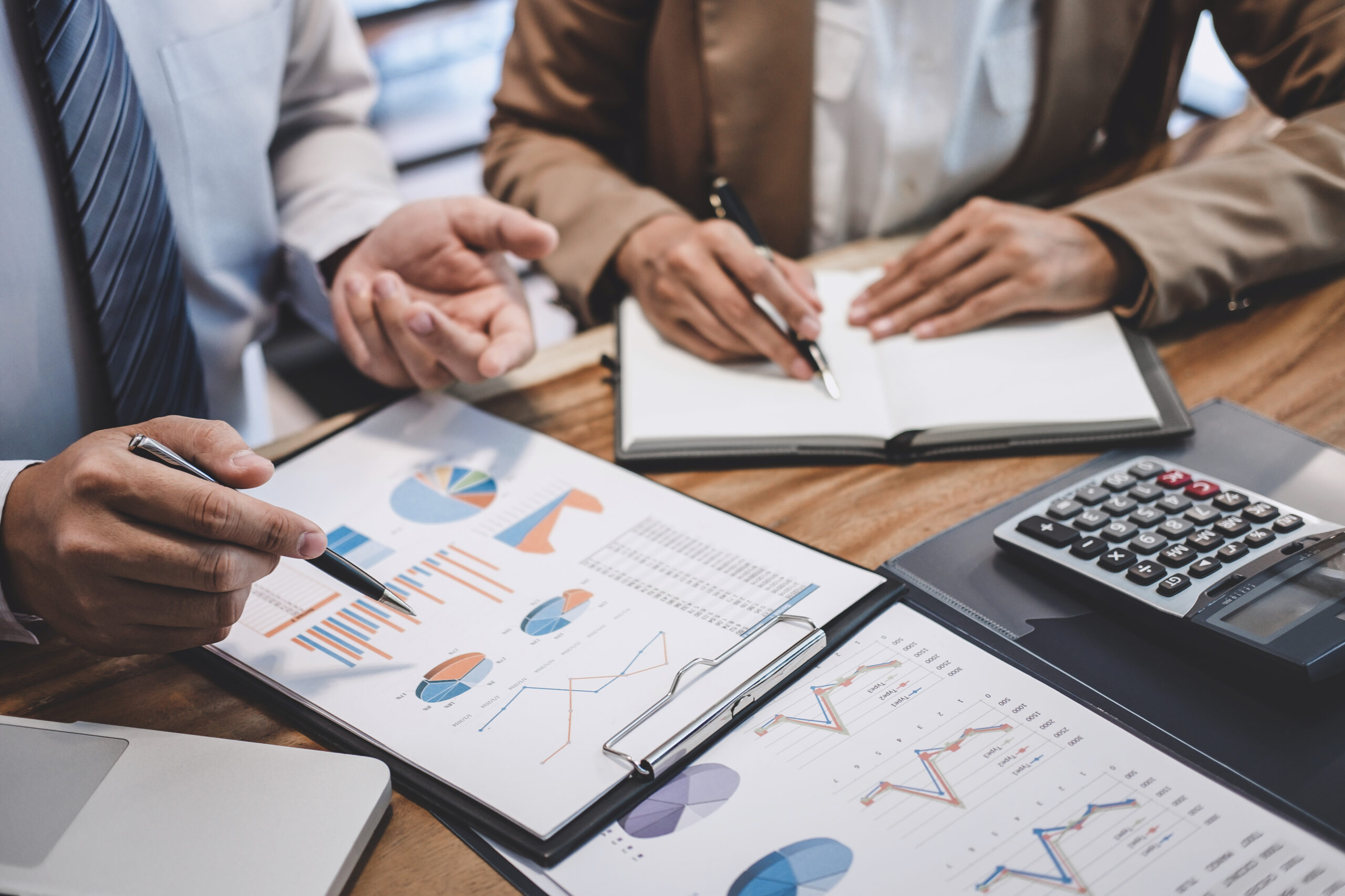 Two professionals with charts on clipboards planning about sales and marketing strategies