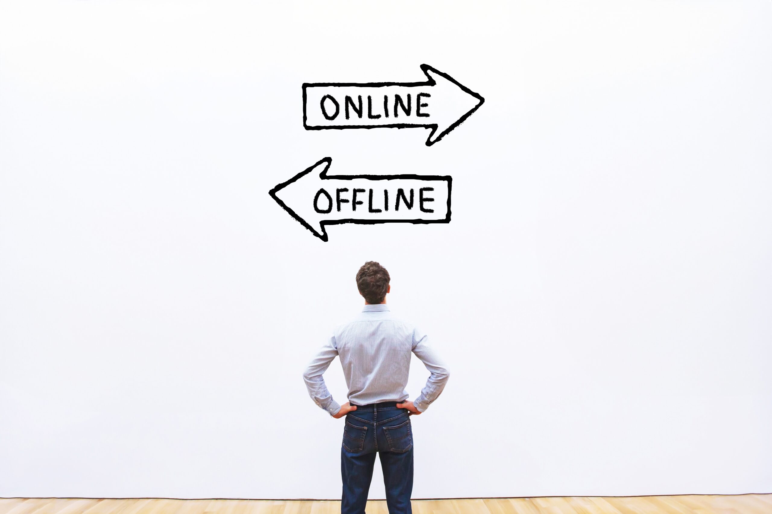 A man looking at a wall with two arrows in opposite directions comparing online and offline direct marketing