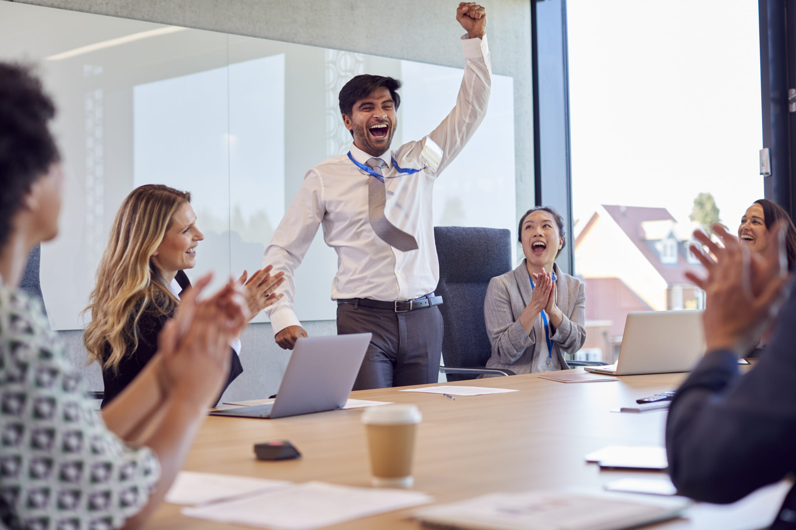 A male employee celebrating with his team because of job promotion.