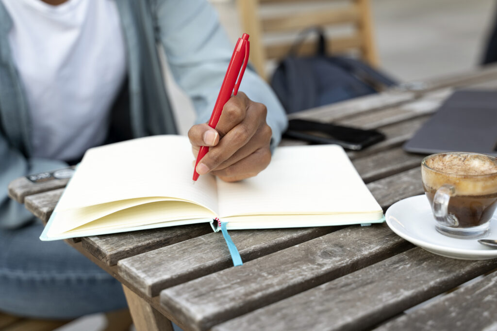 A person writing on a notebook about his professional growth plan.